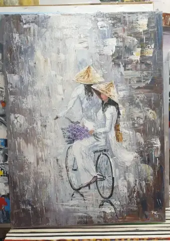 円錐形の帽子をかぶり、紫の花を載せた自転車に乗る白いアオザイの女性の油絵